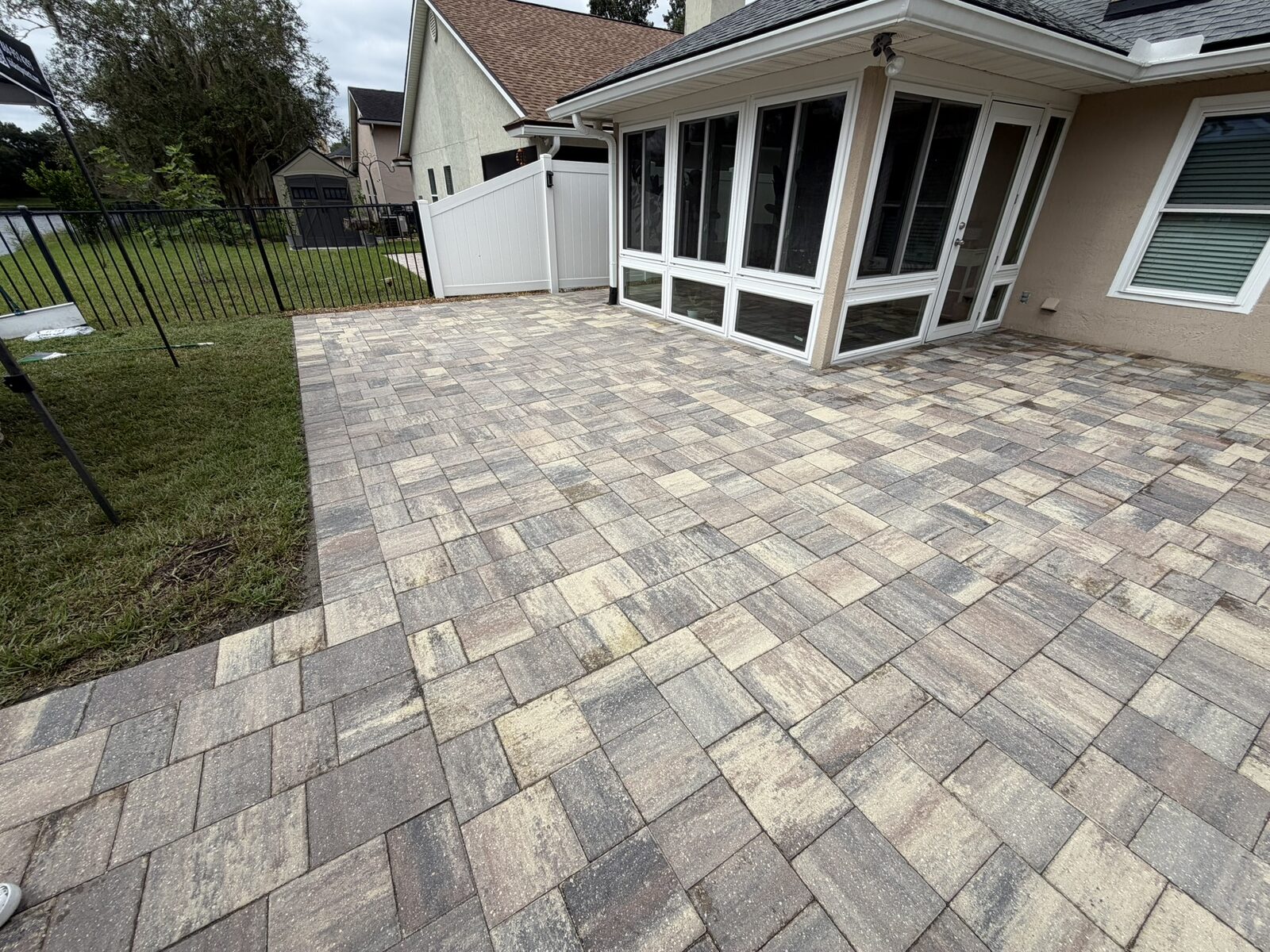 Paver patio beside a screened porch before cleaning
